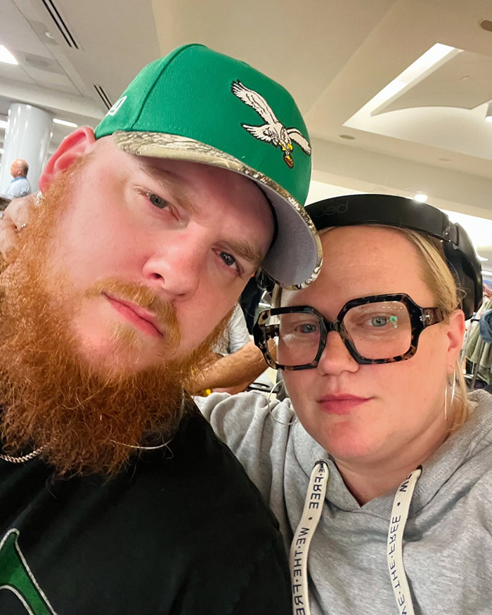 A couple posing together indoors, woman wearing large glasses; highlighting how husband showers. A couple posing together indoors, woman wearing large glasses; highlighting how husband showers.