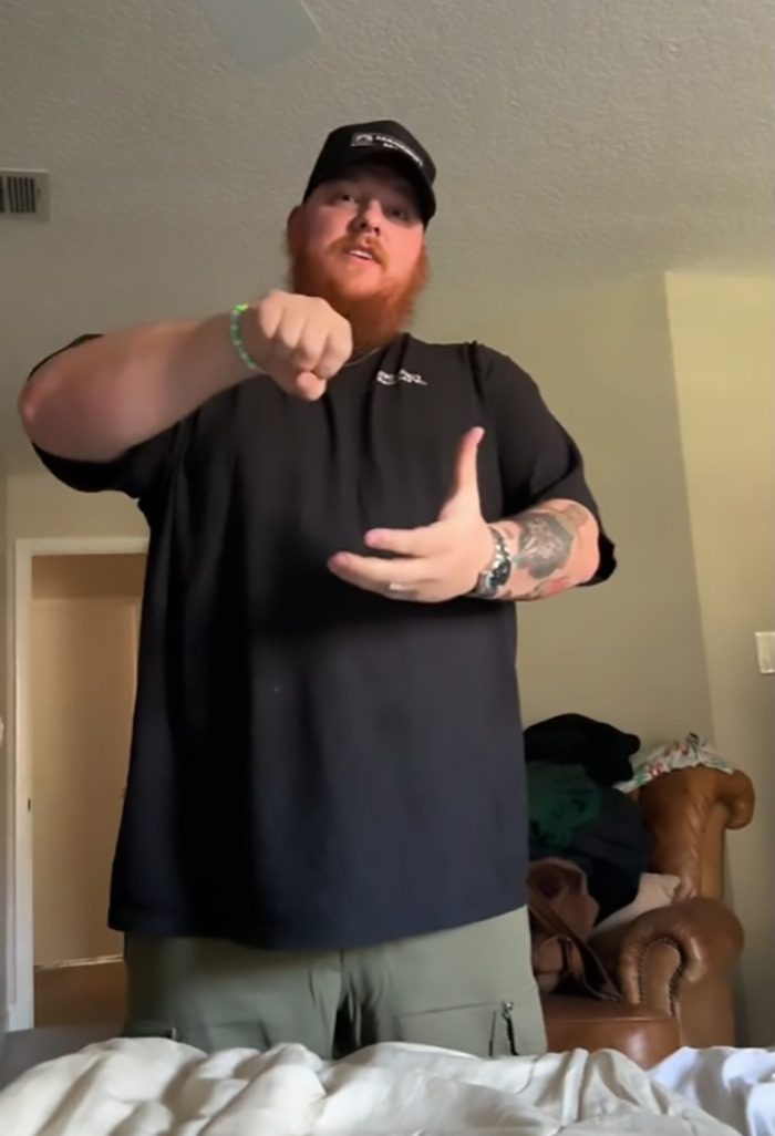Man demonstrating a shower routine in a viral clip, wearing a black shirt and cap. Man demonstrating a shower routine in a viral clip, wearing a black shirt and cap.