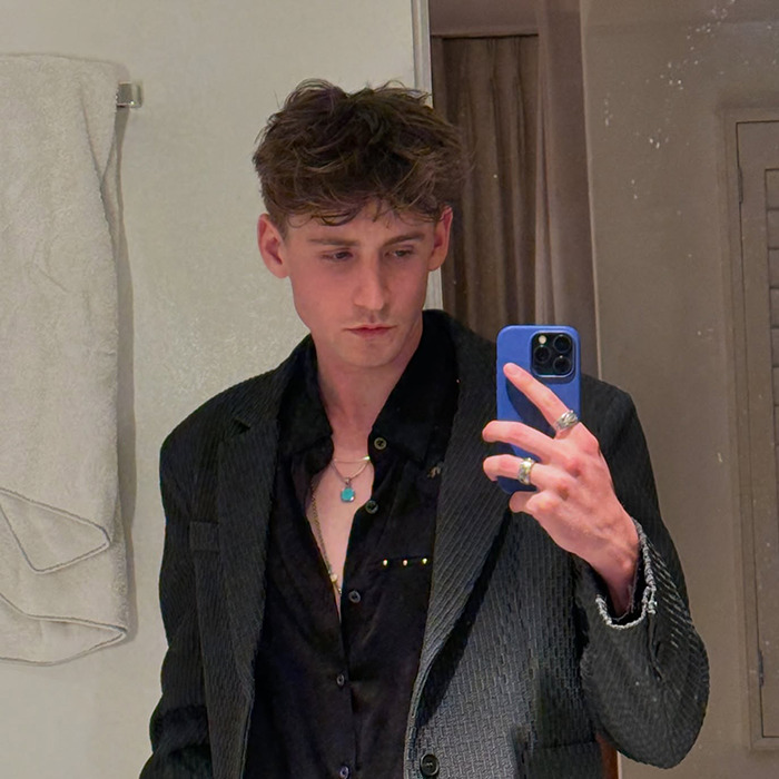 Magnus Ferrell in a black shirt and blazer taking a mirror selfie. Magnus Ferrell in a black shirt and blazer taking a mirror selfie.