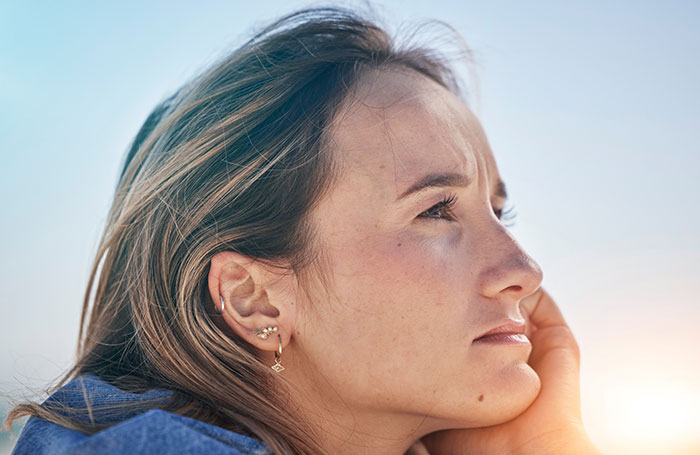 Woman with short hair looks thoughtful against a clear sky, highlighting assumptions about her appearance. Woman with short hair looks thoughtful against a clear sky, highlighting assumptions about her appearance.