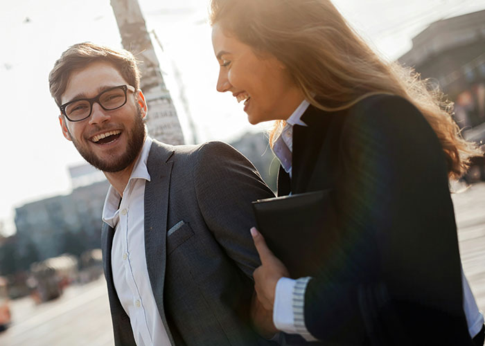 Man and woman in business attire walking and laughing, illustrating the concept of a "work wife". Man and woman in business attire walking and laughing, illustrating the concept of a "work wife".