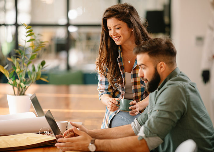 Man and woman working closely on a laptop in an office setting, illustrating the concept of a "work wife. Man and woman working closely on a laptop in an office setting, illustrating the concept of a "work wife.