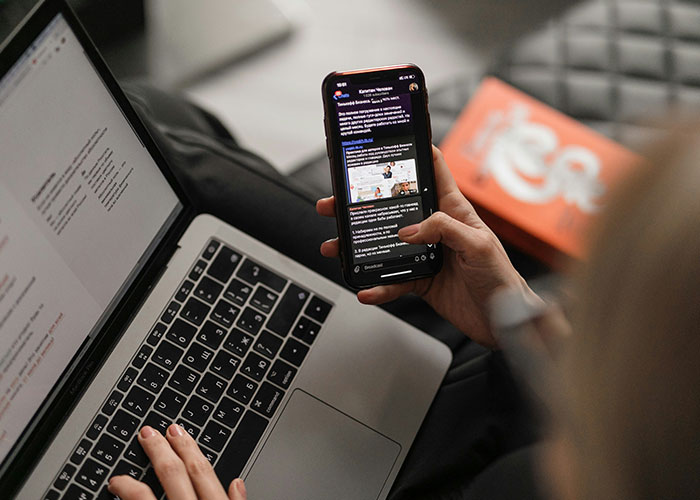 Person using a smartphone while working on a laptop, highlighting the concept of a 'work wife' in professional settings. Person using a smartphone while working on a laptop, highlighting the concept of a 'work wife' in professional settings.