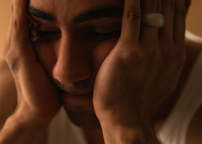 Man in deep thought, resting his face in his hands, conveying the feeling of an outsider in a relationship. Man in deep thought, resting his face in his hands, conveying the feeling of an outsider in a relationship.