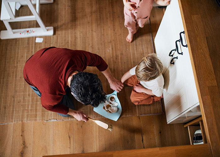 A man practicing gentle parenting, serving snacks to a child on a wooden floor. A man practicing gentle parenting, serving snacks to a child on a wooden floor.