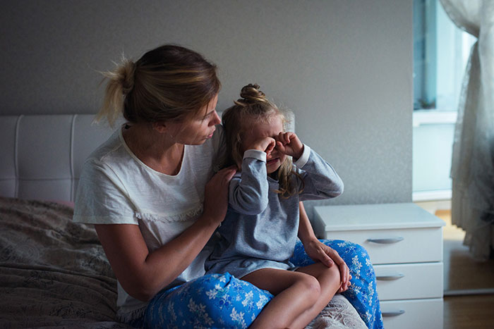 Woman comforting her 7-year-old child at home, excluded from spa day with friends. Woman comforting her 7-year-old child at home, excluded from spa day with friends.