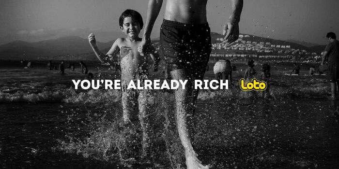 Boy and man happily running through waves, ad campaign emphasizes, "You're Already Rich. Boy and man happily running through waves, ad campaign emphasizes, "You're Already Rich.