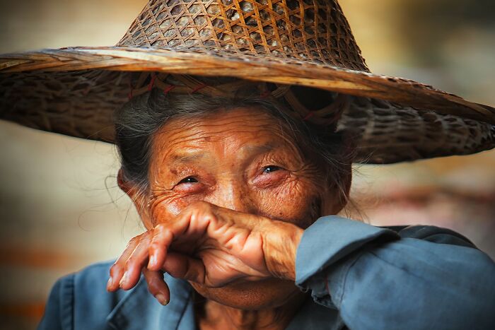 Elderly woman wearing a traditional woven hat, showcasing cultural heritage and ethnicity.