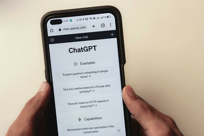 Person holding smartphone displaying ChatGPT interface, discussing environmental impact of AI. Person holding smartphone displaying ChatGPT interface, discussing environmental impact of AI.