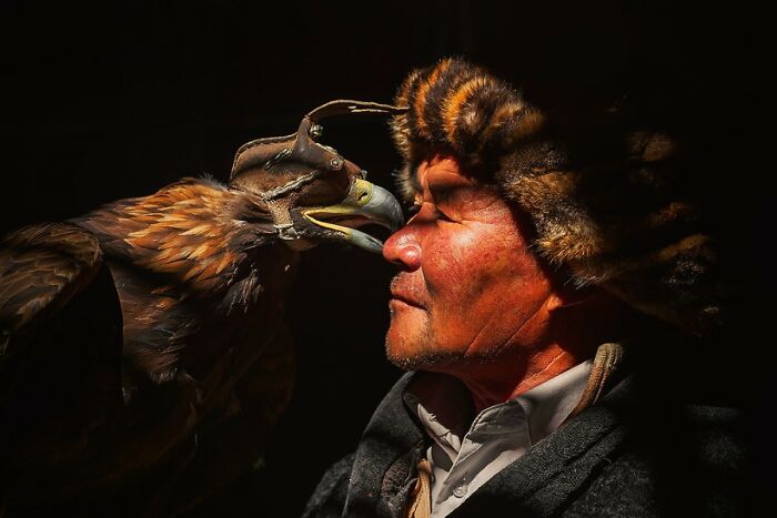 Man in traditional attire with eagle, highlighting global culture and tradition.
