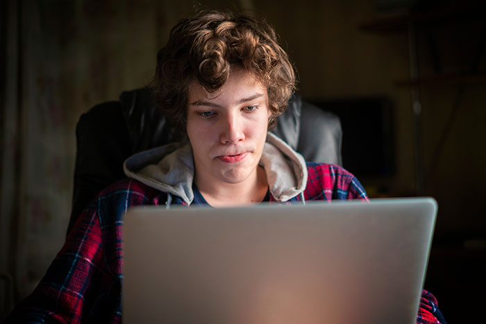 Teen boy focused on a laptop, illustrating themes of neglect contributing to red pill culture dynamics. Teen boy focused on a laptop, illustrating themes of neglect contributing to red pill culture dynamics.