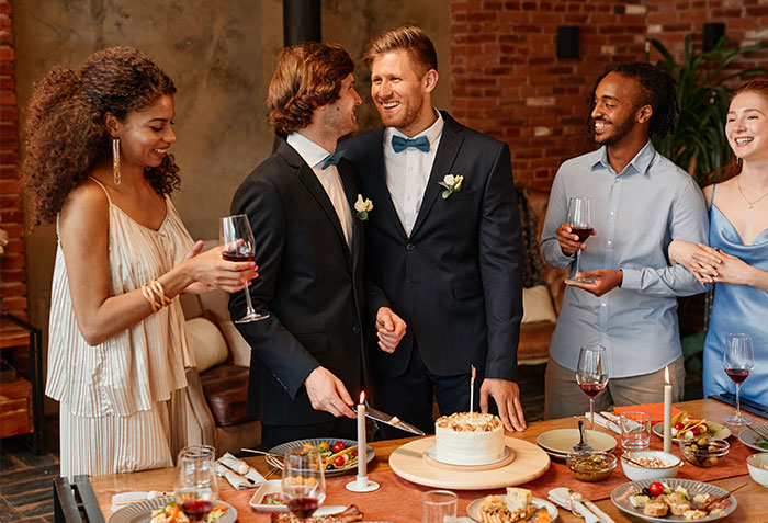 Groom at a dry wedding with friends, smiling and holding a cake knife, amidst laughter and conversation. Groom at a dry wedding with friends, smiling and holding a cake knife, amidst laughter and conversation.