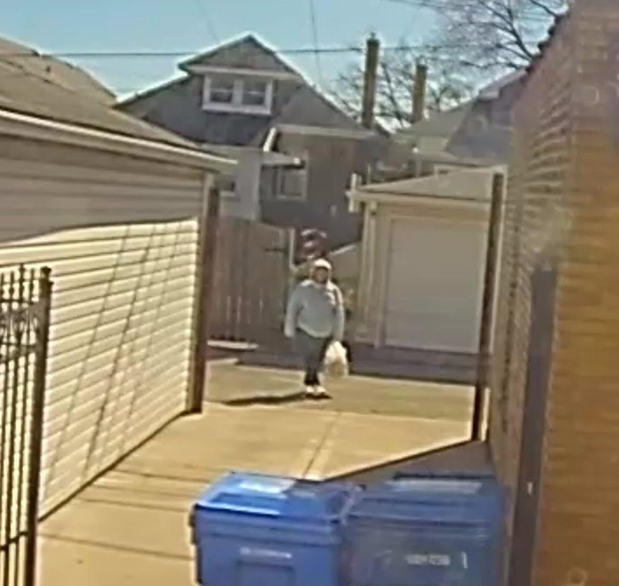 Woman in a residential alley, holding a bag, near garages and garbage bins, related to OCD and fence dispute. Woman in a residential alley, holding a bag, near garages and garbage bins, related to OCD and fence dispute.