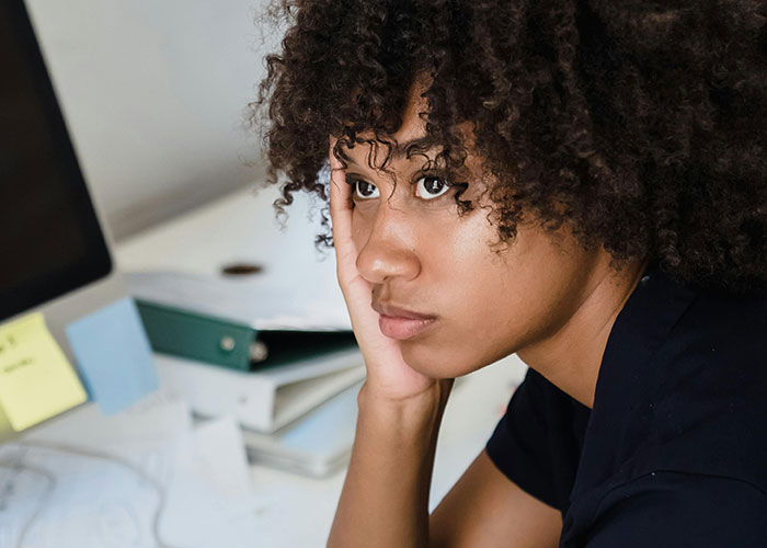 Young woman contemplating beside a desk with folders, reflecting thoughts on property investment and relationships. Young woman contemplating beside a desk with folders, reflecting thoughts on property investment and relationships.