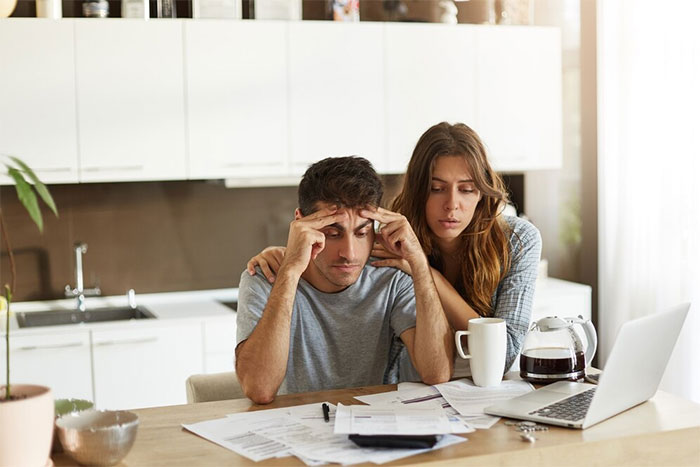 A thoughtful couple reviewing documents at a kitchen table, discussing moving to a blue state. A thoughtful couple reviewing documents at a kitchen table, discussing moving to a blue state.
