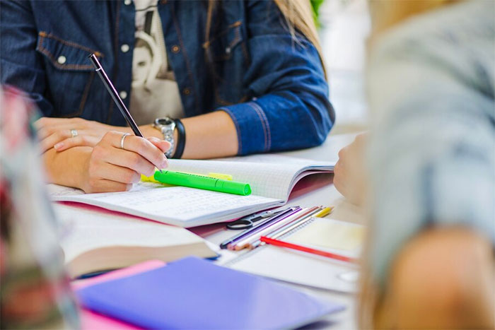 Woman in denim jacket writing notes, highlighting reasons to move to a blue state in a vibrant workspace. Woman in denim jacket writing notes, highlighting reasons to move to a blue state in a vibrant workspace.