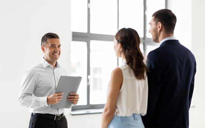 A man with a tablet is smiling at two people in a bright office, highlighting a discussion about moving to a blue state. A man with a tablet is smiling at two people in a bright office, highlighting a discussion about moving to a blue state.