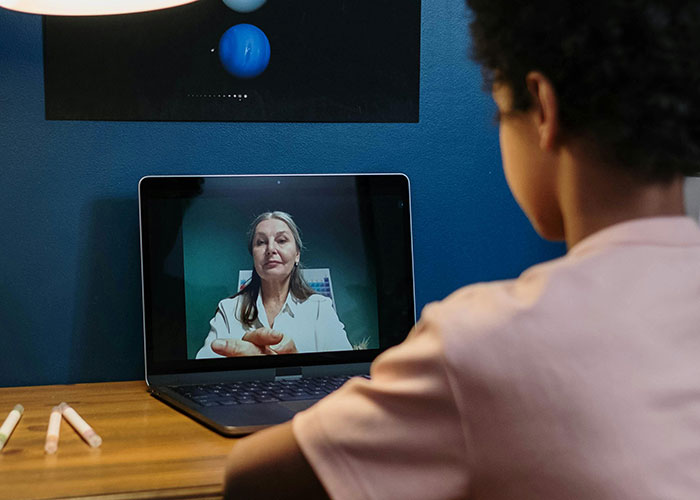 Child video chatting with a teacher on a laptop, discussing name pronunciation issues. Child video chatting with a teacher on a laptop, discussing name pronunciation issues.