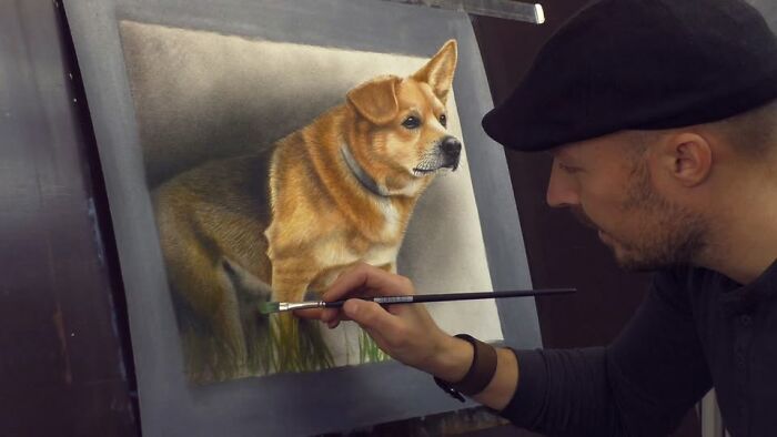 A professional artist in a black hat skillfully painting a realistic 3D dog portrait.