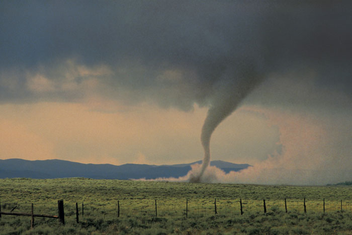 Tornado touching down in a field, showcasing a natural disaster that could help save someone's life by recognizing weather patterns.