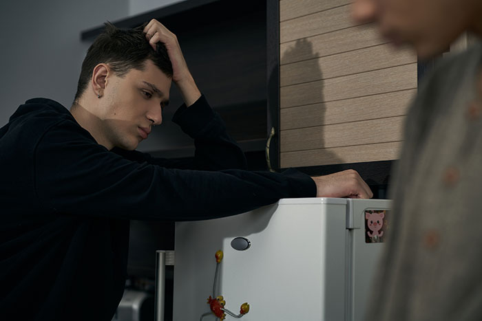 Man searching a nearly empty fridge, looking concerned, related to food and fat-shaming issues among roommates. Man searching a nearly empty fridge, looking concerned, related to food and fat-shaming issues among roommates.