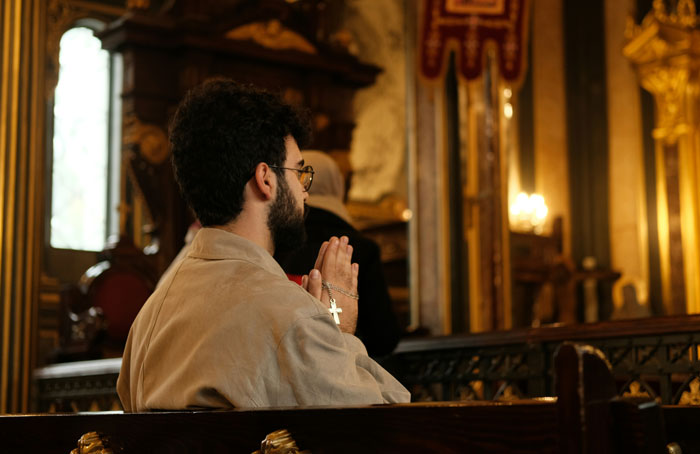 Man praying in church pew, holding rosary, reflecting on gay marriage and faith. Man praying in church pew, holding rosary, reflecting on gay marriage and faith.