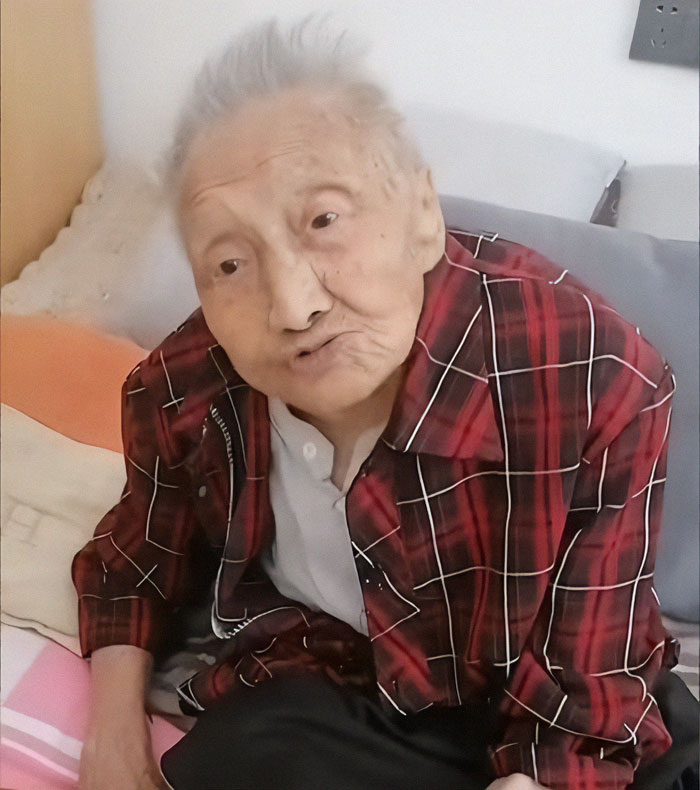Elderly Chinese woman in a red plaid shirt, sitting upright in a chair, reflecting a lifetime of patience and endurance. Elderly Chinese woman in a red plaid shirt, sitting upright in a chair, reflecting a lifetime of patience and endurance.