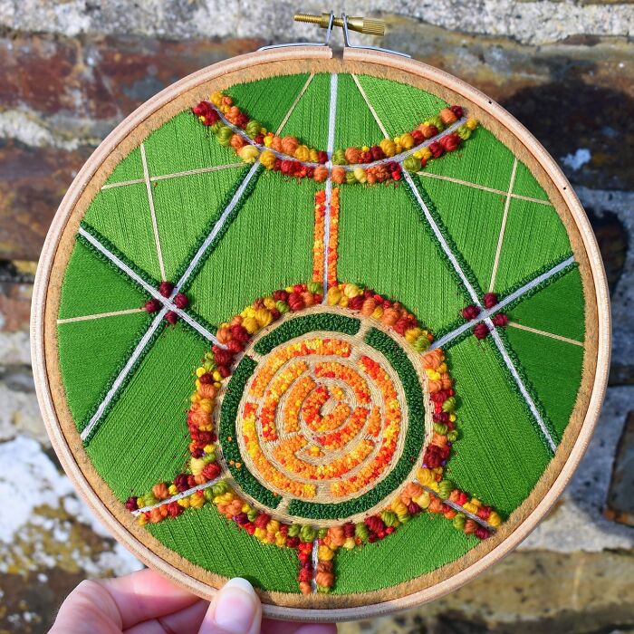 Colorful landscape embroidery with geometric patterns and texture, featuring green and orange hues.
