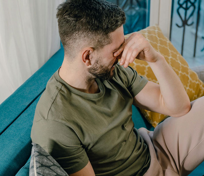 A man on a sofa appears deep in thought, wearing a green shirt, symbolizing contemplation about his marriage and church beliefs. A man on a sofa appears deep in thought, wearing a green shirt, symbolizing contemplation about his marriage and church beliefs.
