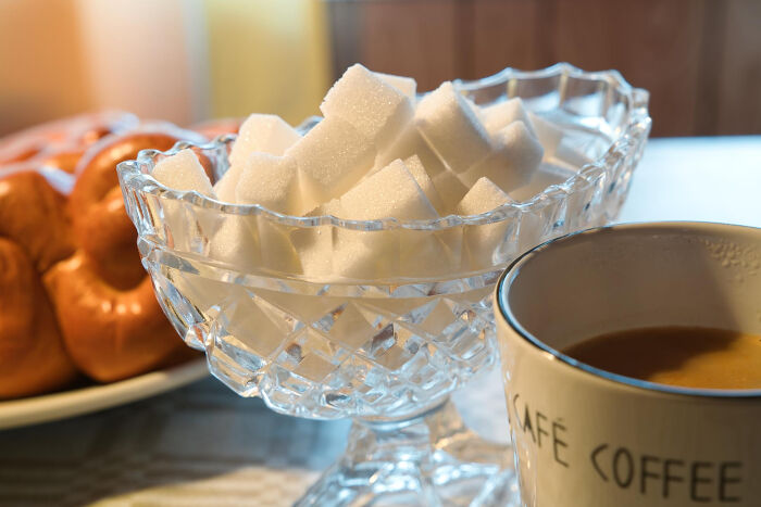 Crystal bowl of sugar cubes next to a coffee mug, ideal for harmless April Fools' pranks.
