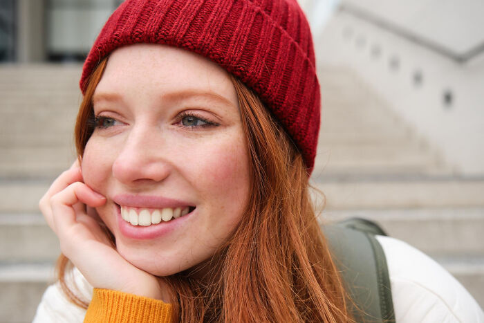 Smiling woman in a red beanie, showcasing a fun and light-hearted vibe suitable for harmless April Fools' pranks.