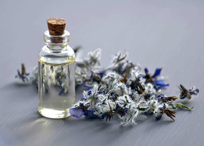 A small bottle of essential oil beside dry flowers showcasing a beauty tip.