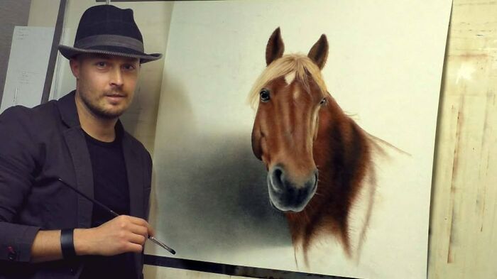 German artist showcasing his incredible 3D drawing of a horse, wearing a hat and holding a brush.