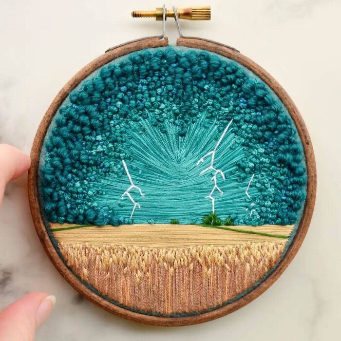 Embroidery of a wheat field with stormy sky and lightning, showcasing landscape embroidery artistry.