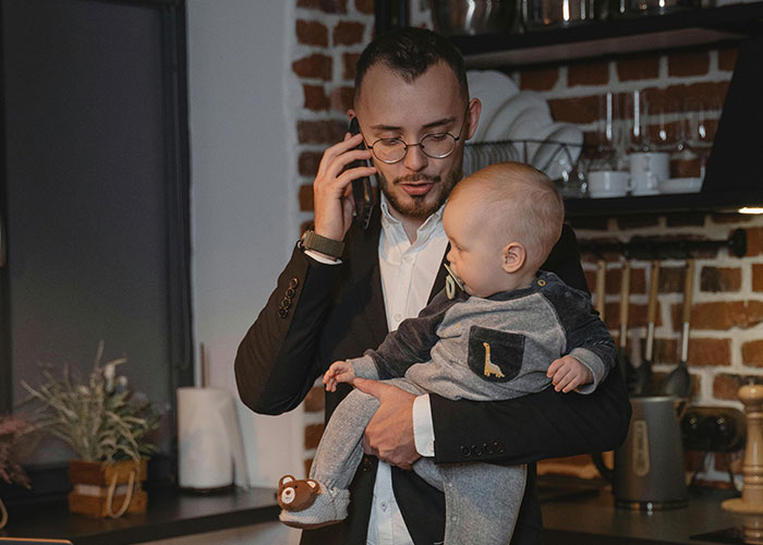 Man holding baby in a kitchen, multitasking while on the phone. Man holding baby in a kitchen, multitasking while on the phone.