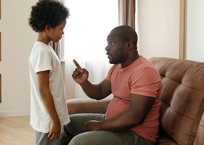 A parent gently explains something to a child, highlighting gentle parenting techniques on a living room couch. A parent gently explains something to a child, highlighting gentle parenting techniques on a living room couch.