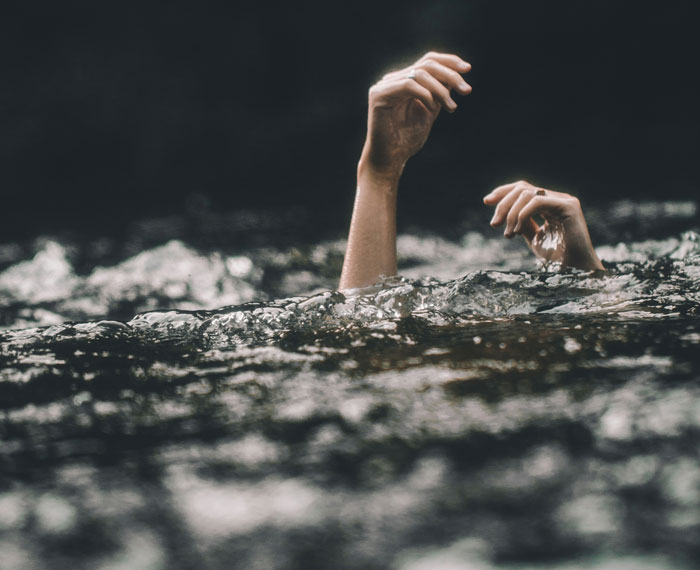 Hands reaching above water, potentially illustrating a life-saving scenario.