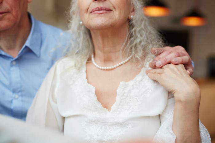 Elderly woman in a white dress with pearls at a wedding, emphasizing her attire choice. Elderly woman in a white dress with pearls at a wedding, emphasizing her attire choice.