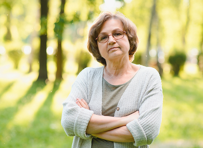 Woman outdoors with crossed arms and glasses, related to OCD and a neighbor's fence issue. Woman outdoors with crossed arms and glasses, related to OCD and a neighbor's fence issue.