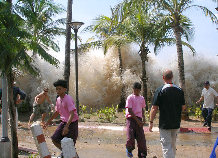 People fleeing a massive wave crashing on a beach, signifying a creepy photo with a dark history. People fleeing a massive wave crashing on a beach, signifying a creepy photo with a dark history.