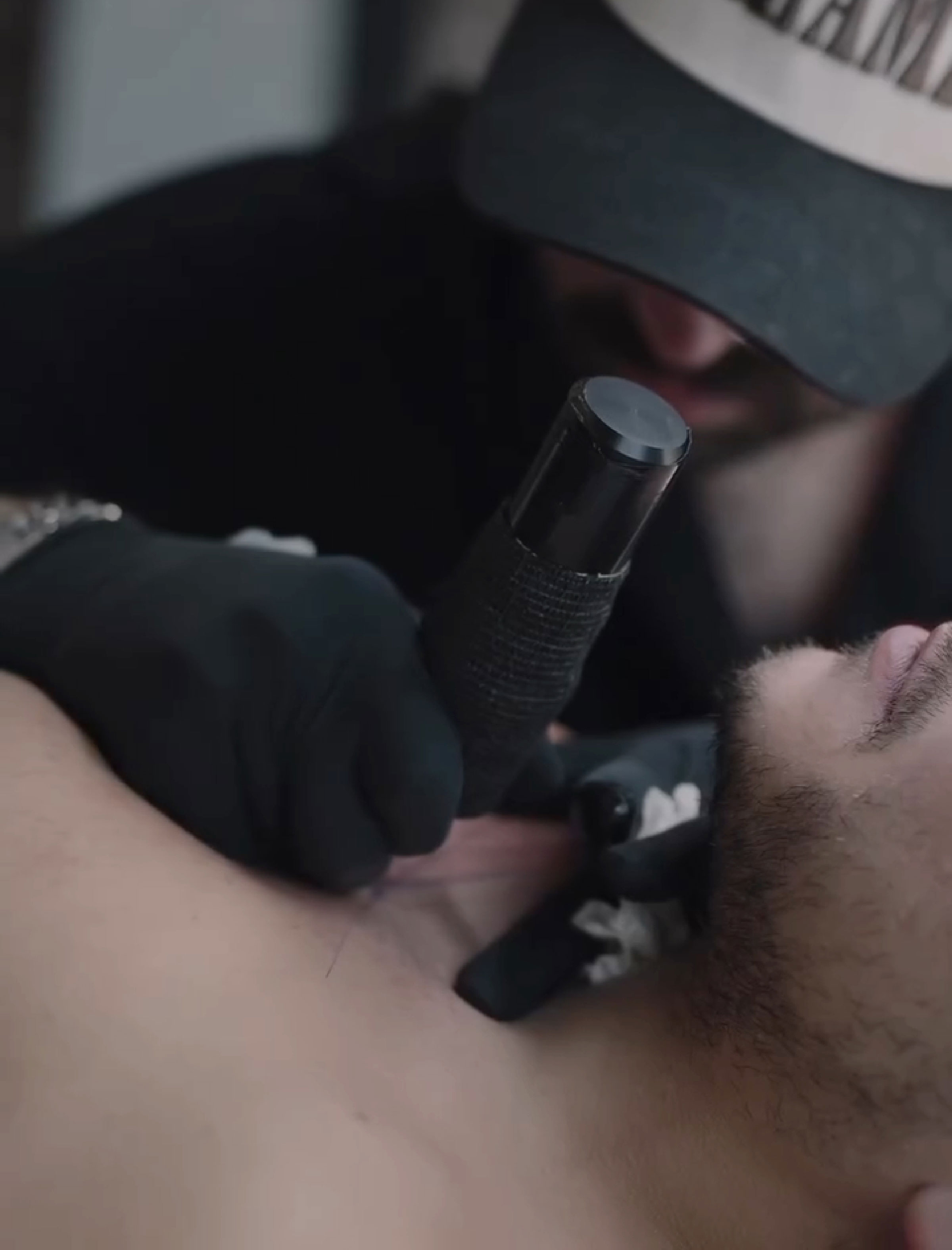 Tattoo artist working, wearing a cap, crafts unique brain activity-inspired tattoo on a man's chest. Tattoo artist working, wearing a cap, crafts unique brain activity-inspired tattoo on a man's chest.