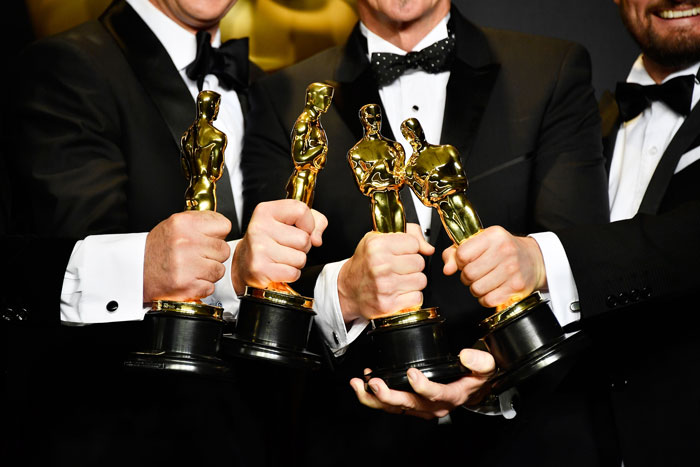 Winners holding Oscars 2025 awards, dressed in tuxedos, celebrating victory. Winners holding Oscars 2025 awards, dressed in tuxedos, celebrating victory.