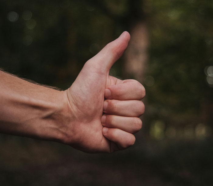 Thumbs up hand gesture outdoors, symbolizing positive life-saving facts.