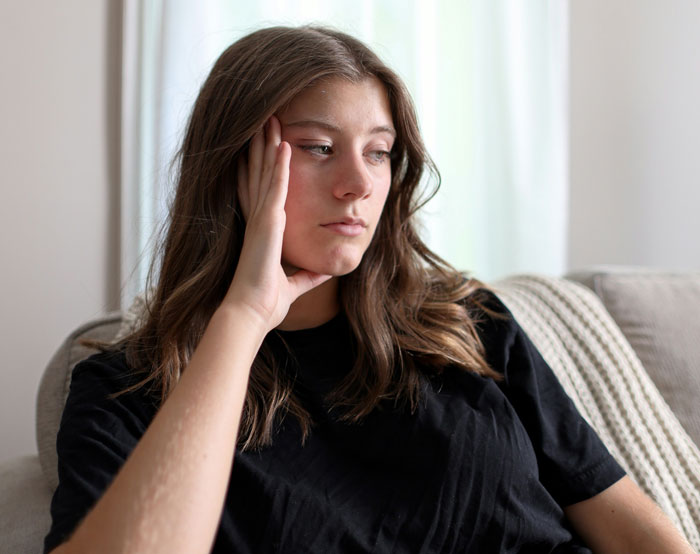 Woman looking thoughtful on a couch, considering babysitting offer for $3 an hour. Woman looking thoughtful on a couch, considering babysitting offer for $3 an hour.