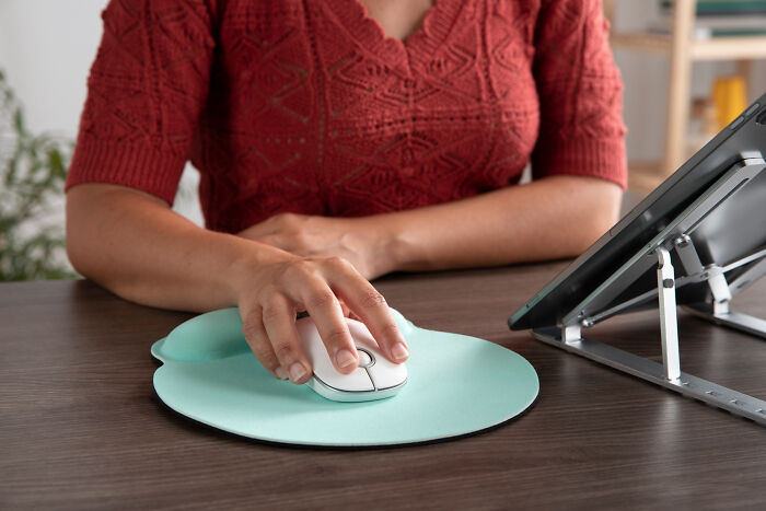 Person using a computer mouse on a humorous mouse pad, ideal for harmless April Fools' pranks at the office.