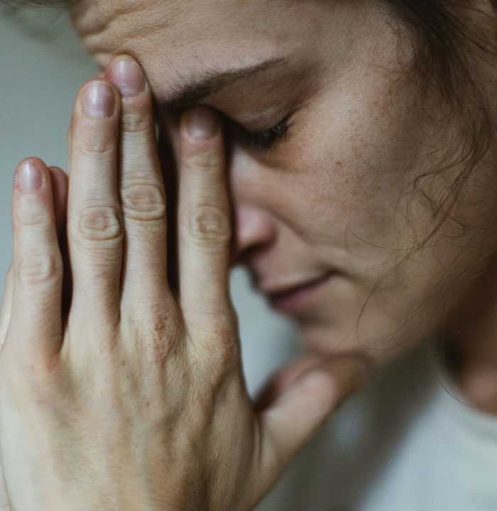 A worried woman with hands on face, illustrating babysitting struggle. A worried woman with hands on face, illustrating babysitting struggle.