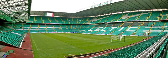 Panoramic view of a historic soccer stadium with green seats and well-maintained pitch, a cathedral of soccer legends.