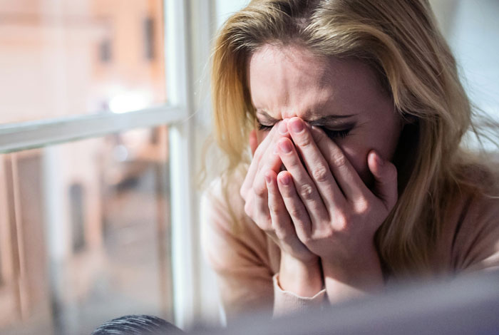 Upset woman covering face, related to babysitting demands. Upset woman covering face, related to babysitting demands.