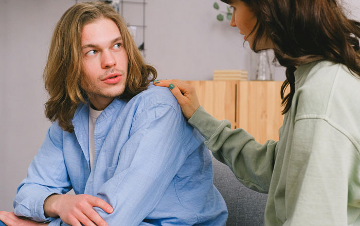 Man in blue shirt being comforted by a woman in green, related to babysitting job demand. Man in blue shirt being comforted by a woman in green, related to babysitting job demand.