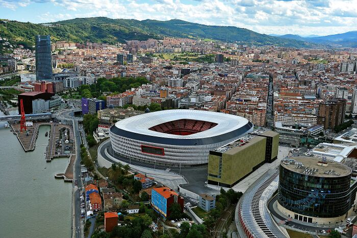Aerial view of a famous soccer cathedral stadium surrounded by cityscape and hills where legends are born.
